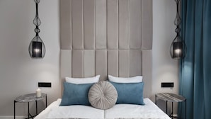 A modern bedroom with a tufted headboard, two bedside tables, a round table, and a decorative pillow. - Elite Apartments Ogarna Prestige (Gdansk)