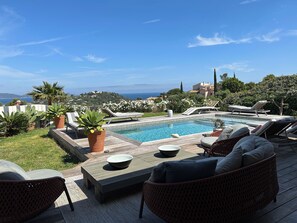 Un espace aménagé au bord de la piscine, avec des chaises longues, une table et des plantes en pot.