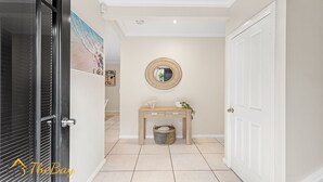 A hallway with a wooden console table, a round mirror, and a white door.