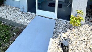 A house with a large window, a small patio, and a flag. - Vacation in Paradise on the Canal w/Heated Pool, minutes to Beach, Dog Friendly! (Rotonda West)