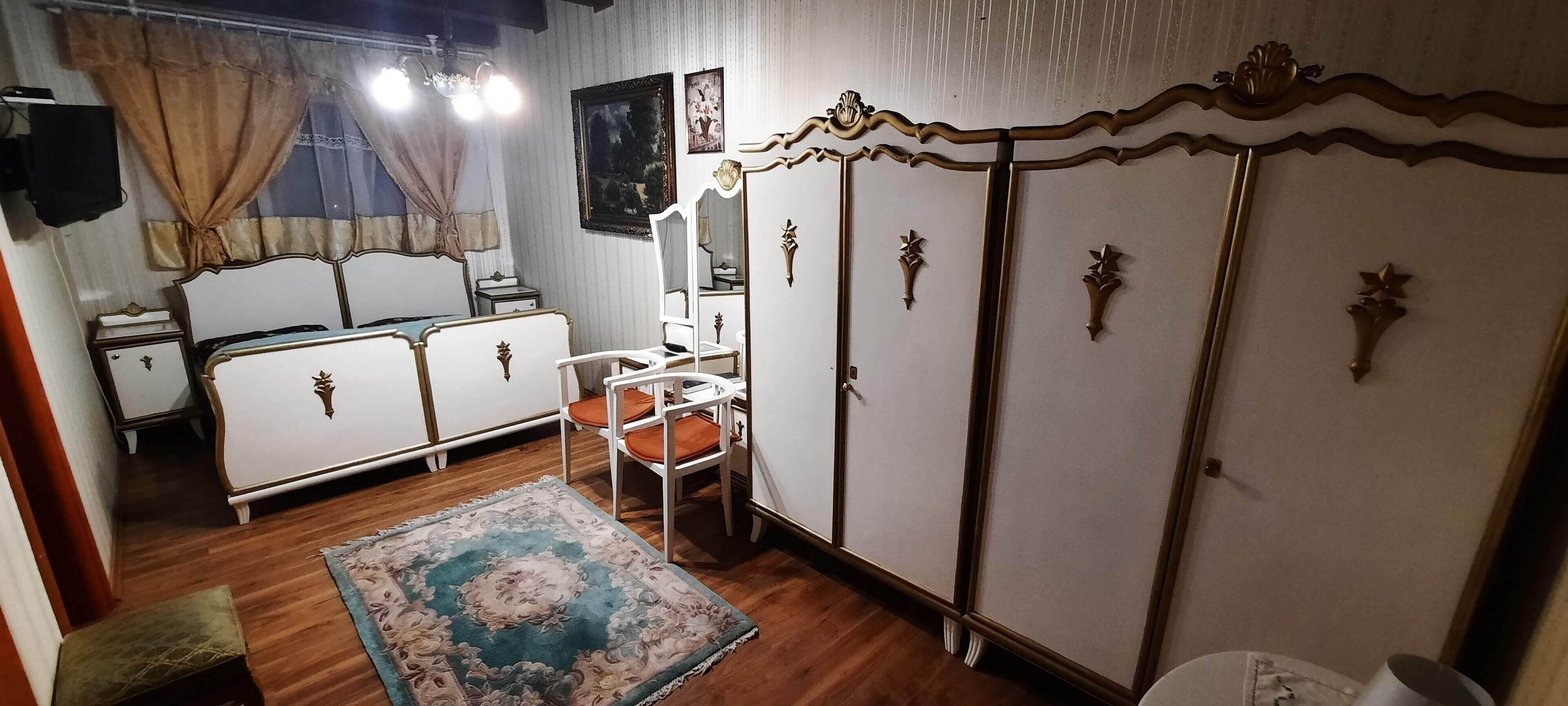 Ein Schlafzimmer mit einem Bett, einem Kleiderschrank, einem Sessel und einem Teppich.
