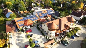 Eine Vogelperspektive auf ein Wohngebiet mit Häusern, Solaranlagen auf den Dächern und einem Parkplatz mit Autos.
