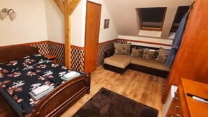 Ein Schlafzimmer mit einem Bett, einem Nachttisch, einer Lampe und einer kleinen Sitzecke mit Kissen.
