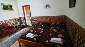 Een kamer met een bed, een stoel, een bureau en een deur naar buiten.