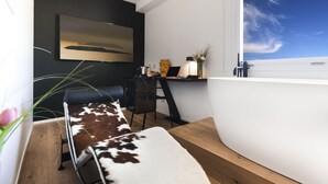 A modern room with a large window, a desk with a computer, a chair, and a sofa with a cowhide cover. - MICELI EXCLUSIVE SUITE (Palermo)