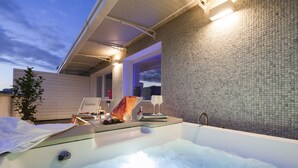 A hot tub with a tiled wall and a window, a towel, and a glass of wine on the side. - MICELI EXCLUSIVE SUITE (Palermo)