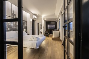 A modern hotel room with a large bed, a desk, and a view of the cityscape through floor-to-ceiling windows. - MICELI EXCLUSIVE SUITE (Palermo)