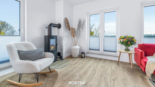 En moderne stue med pejs, gyngestol og en rød sofa.