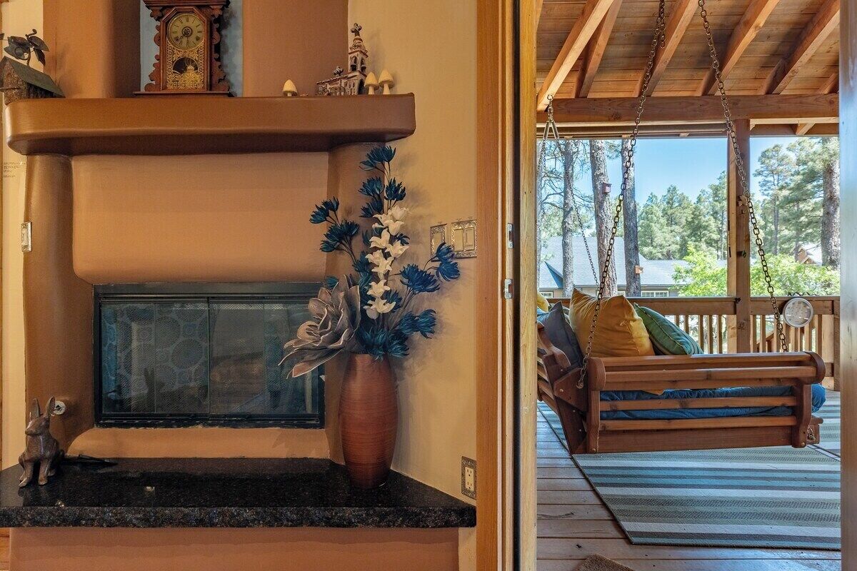 Un intérieur chaleureux avec une cheminée, un banc en bois et une vue sur l’extérieur.