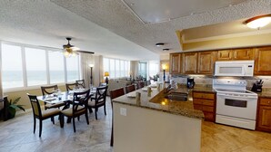 A spacious kitchen with granite countertops, wooden cabinets, and a view of the ocean.