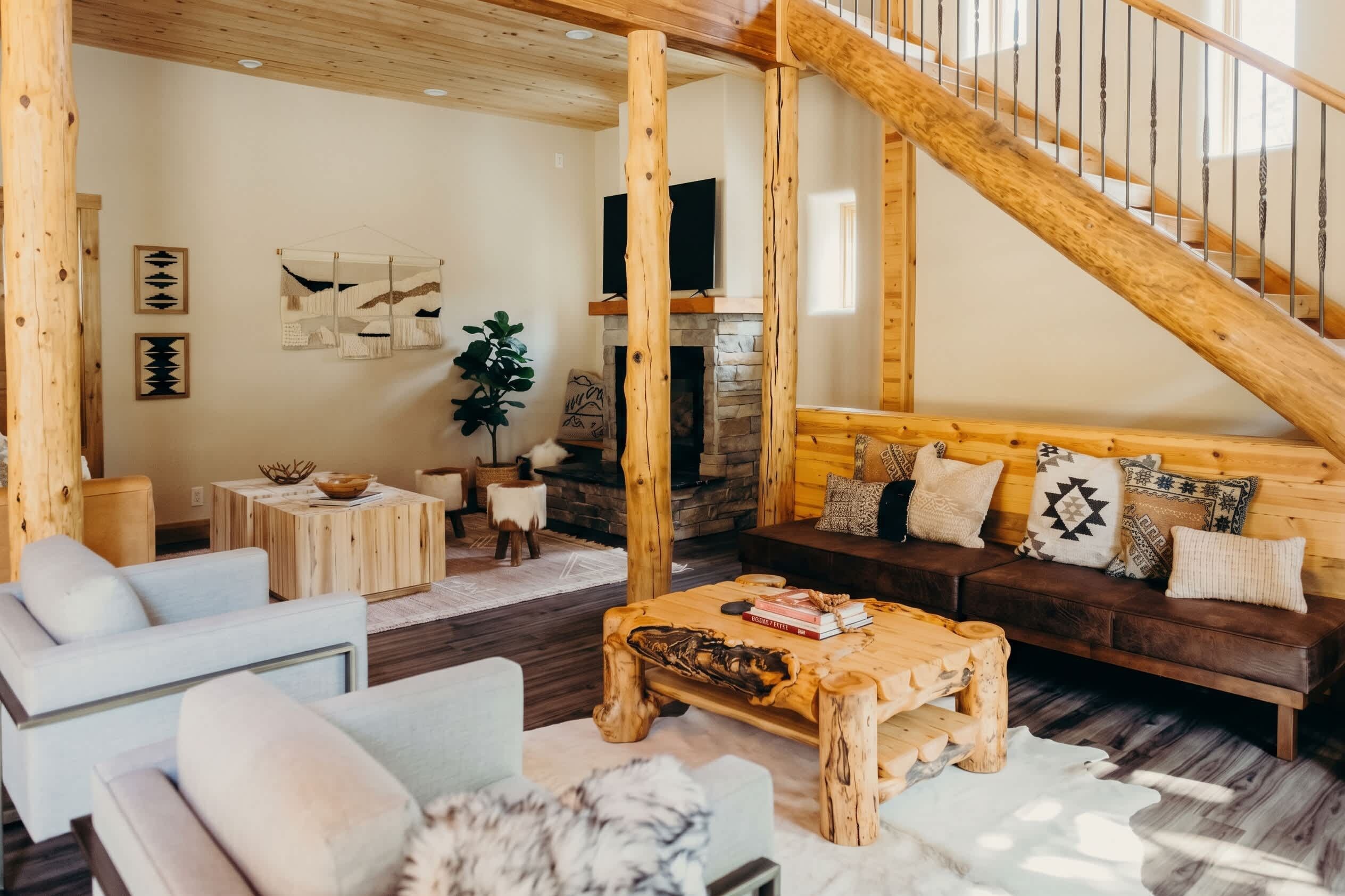 A cozy living room with a wooden staircase, a fireplace, and a sofa with patterned cushions.