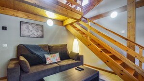 Un salon moderne avec un escalier en bois, un canapé, une table basse et une carte du monde accrochée au mur.