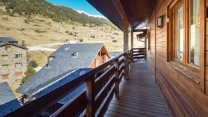 Une cabane en bois dotée d’un balcon donnant sur un paysage montagneux.