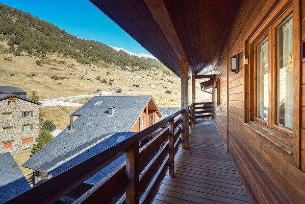 Une cabane en bois dotée d’un balcon donnant sur un paysage montagneux.