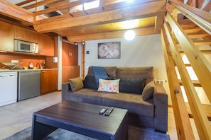 Un intérieur en bois comprenant un canapé, une table basse et un coin cuisine.
