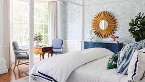 A bedroom with a large bed, a vanity with a mirror, a chair, and a window with curtains. - Spacious Luxurious Townhome - 2 Blocks to Forsyth! (Savannah)