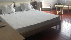 Une chambre d’hôtel avec un grand lit, une table de chevet, une chaise et un petit bureau.