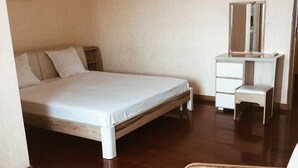 Une chambre à coucher comprenant un lit, une commode, un miroir, une chaise et une petite table.
