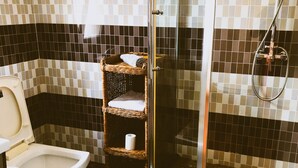 Une salle de bain avec une douche, des toilettes et une étagère en osier.