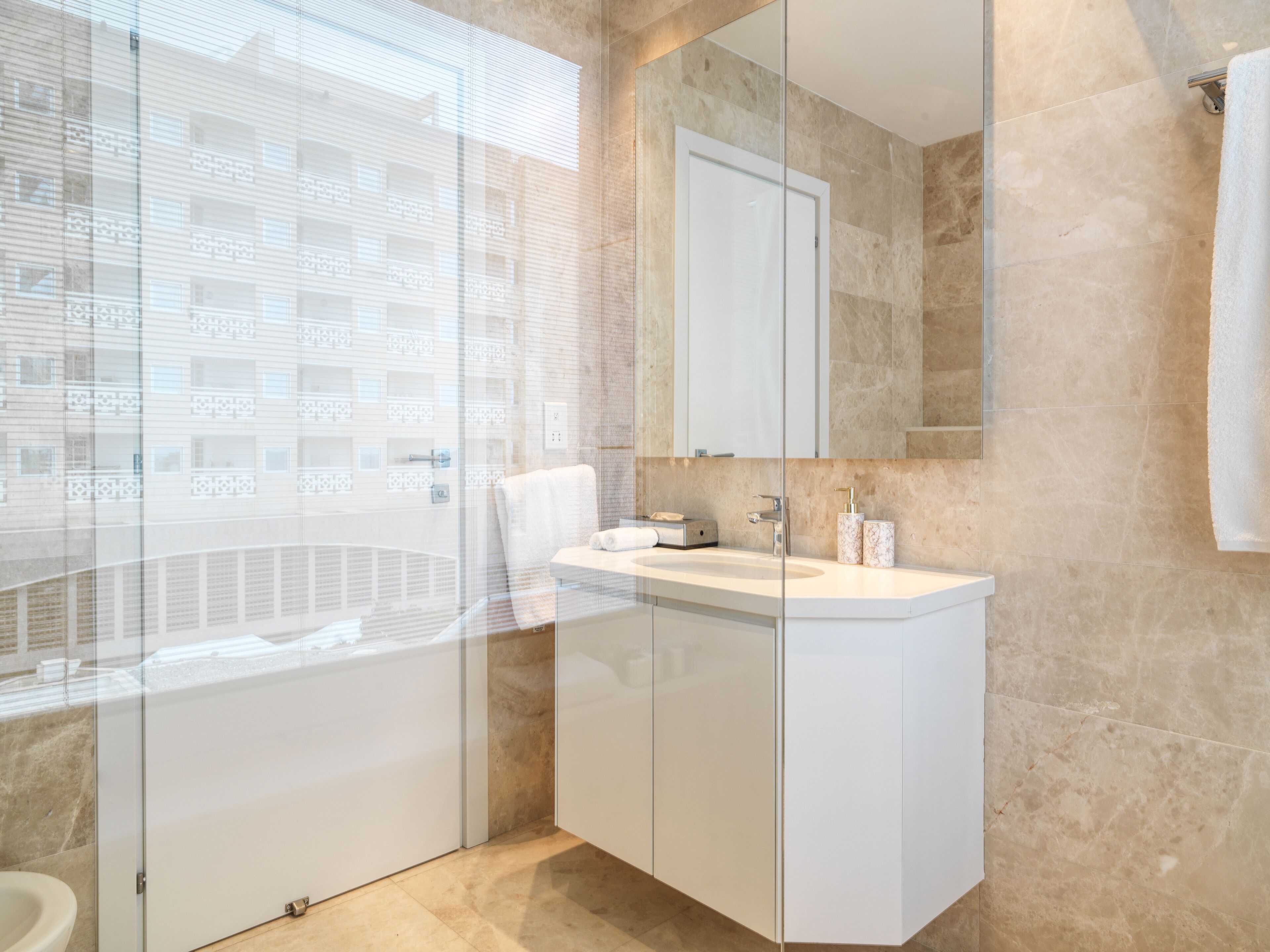 A modern bathroom with a glass shower enclosure, a white sink, and a large mirror.