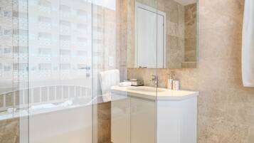 A modern bathroom with a glass shower enclosure, a white sink, and a large mirror.