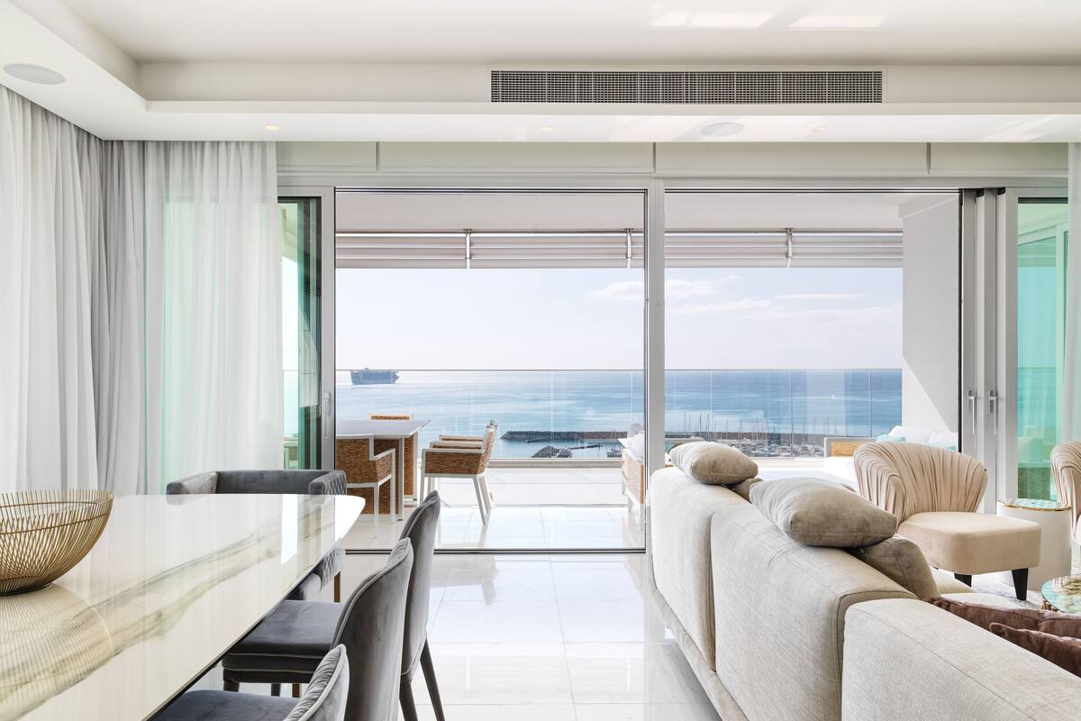 Una sala de estar moderna con balcón, zona de comedor y vista al mar.