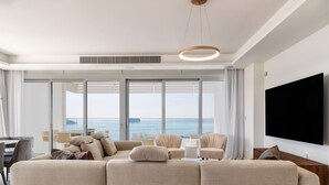 Een moderne woonkamer met een ruime hoekbank, een flatscreen televisie en uitzicht op de oceaan.