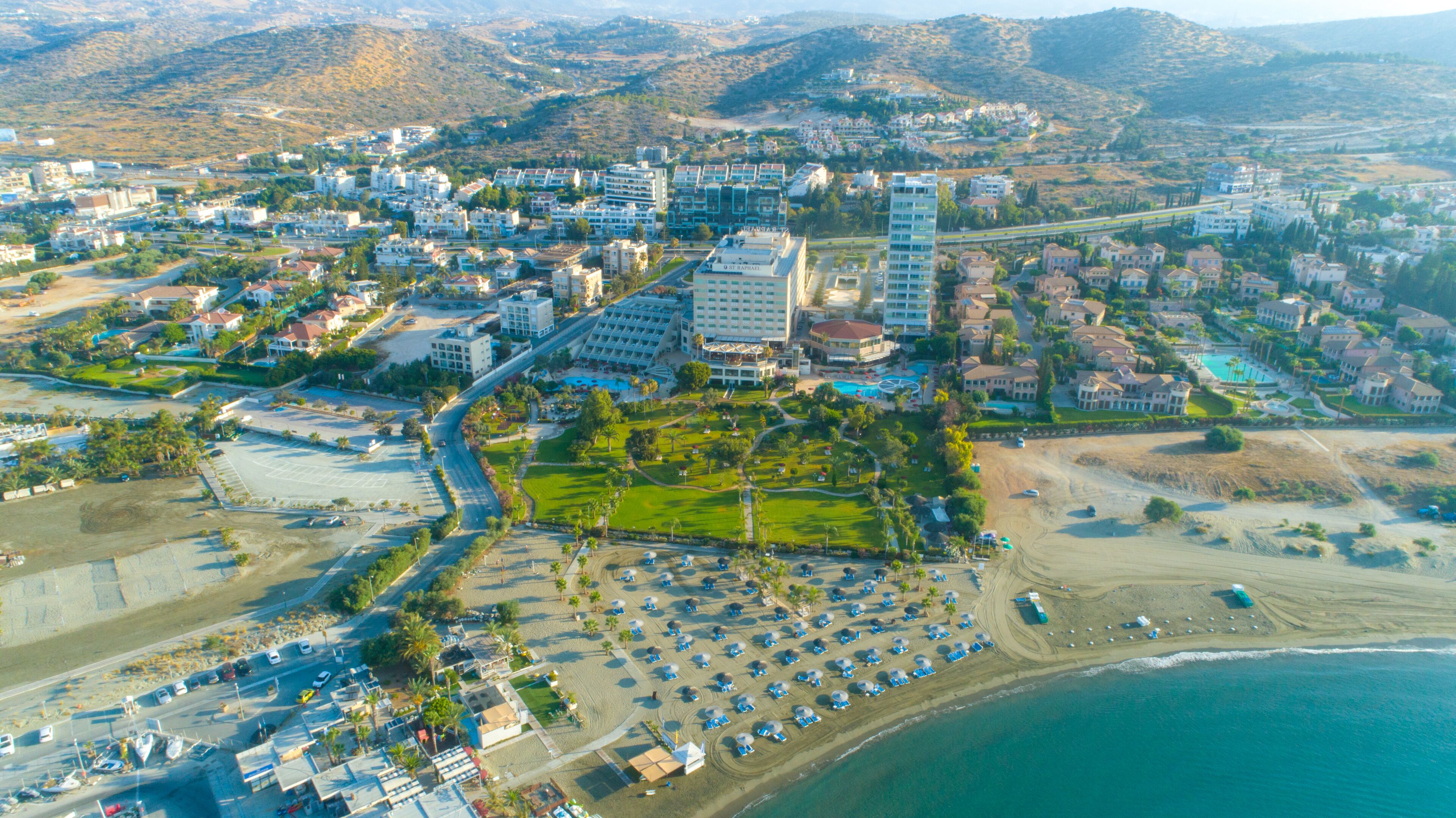 An aerial view of a coastal resort with multiple buildings, a beach, and a parking area.