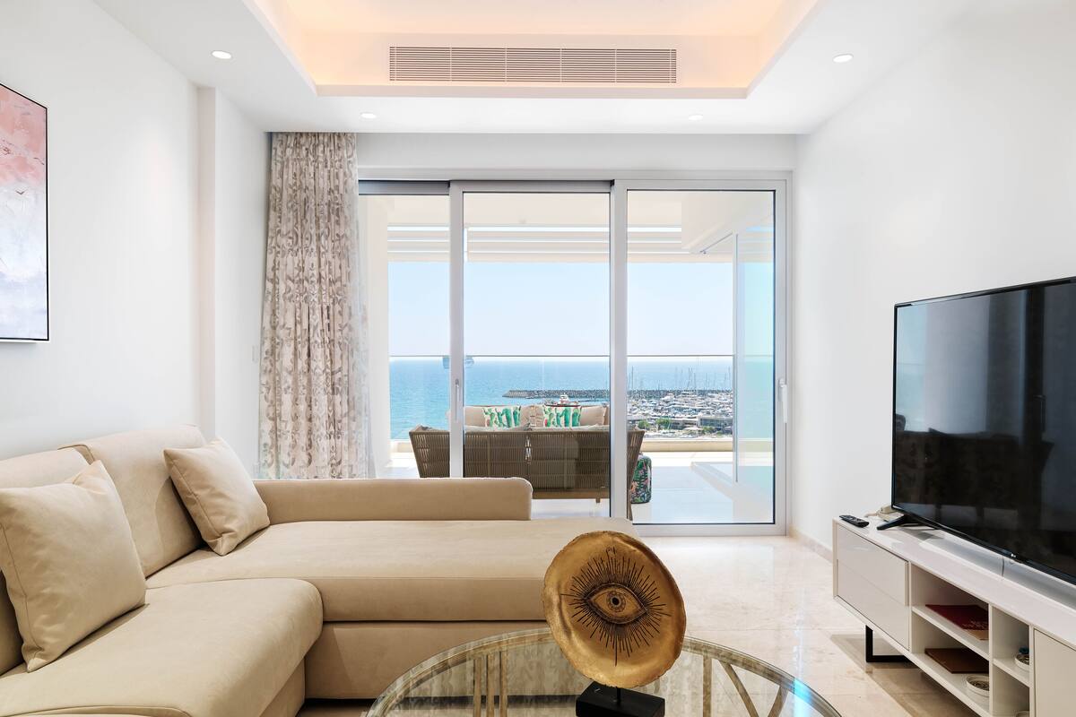 Una sala de estar moderna con un sofá, una mesa de centro de vidrio y un televisor.