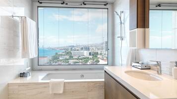 A modern bathroom with a large window, a bathtub, and a vanity with a sink.