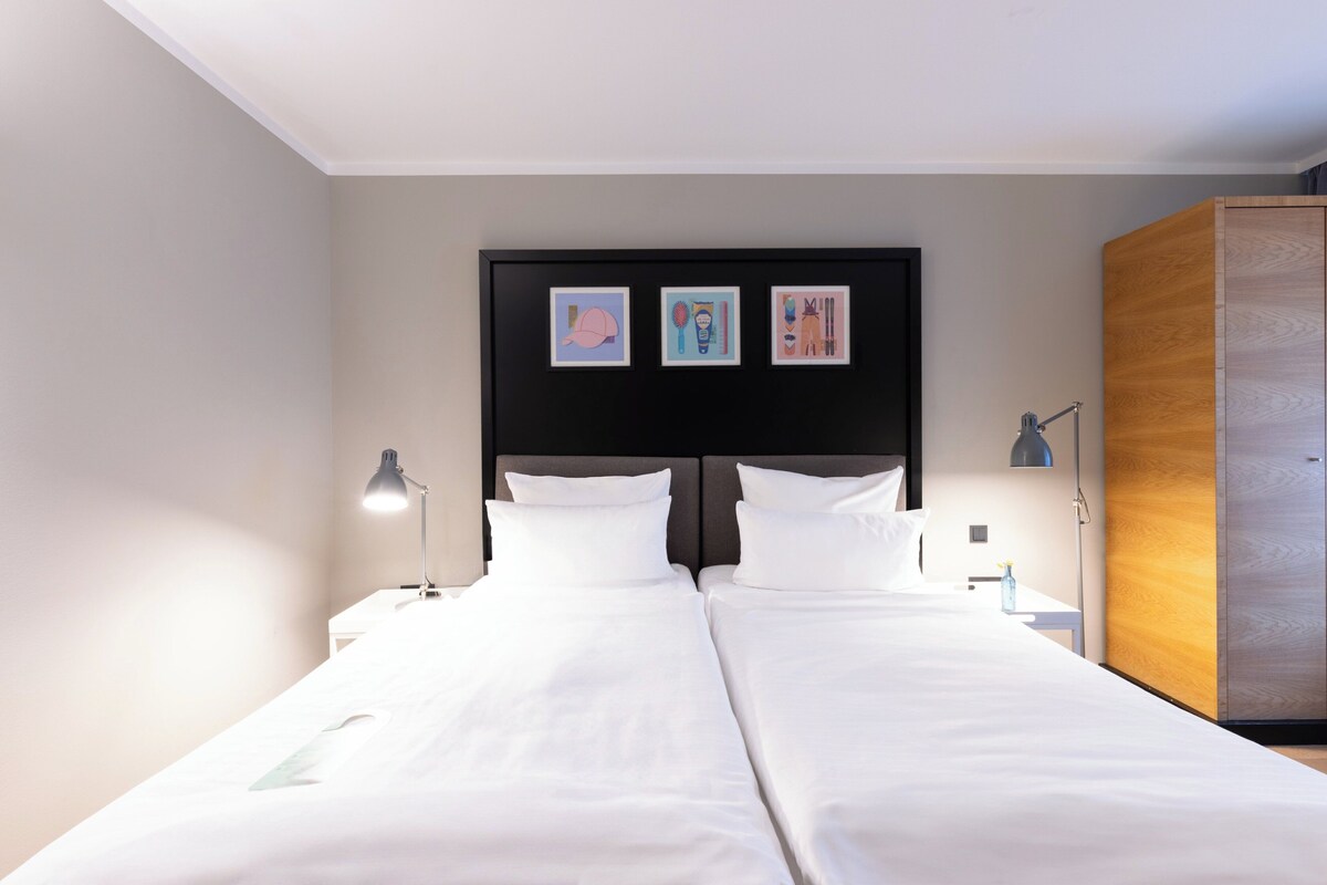 A double bed with white linens, a black headboard, and three framed pictures on the wall.