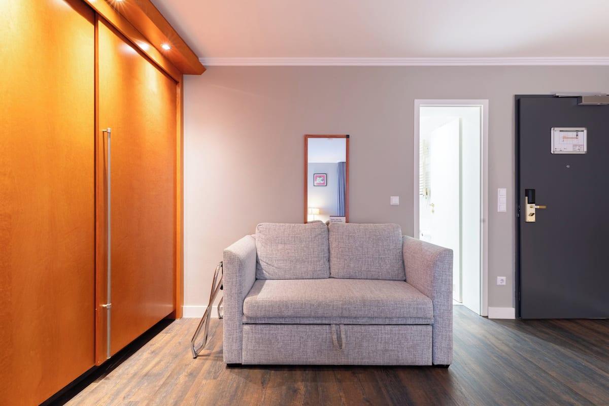 A room with a grey sofa, wooden wardrobe, and a door with a lock.