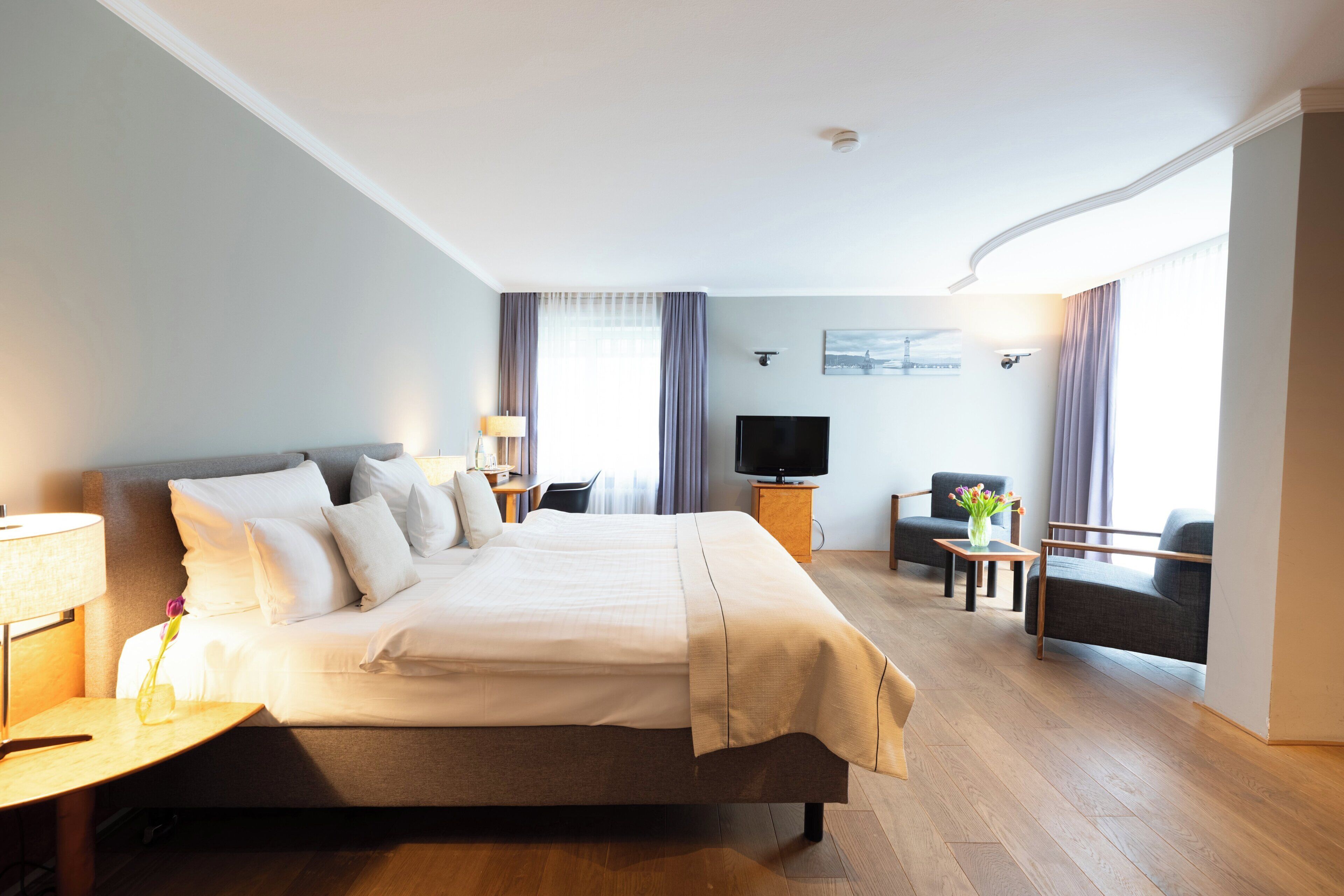 Ein Hotelzimmer mit einem großen Bett, einem Fernseher, einem Schreibtisch und einem Sessel.
