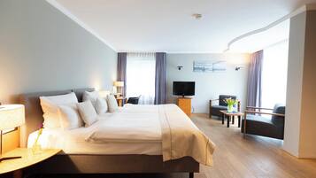 Ein Hotelzimmer mit einem großen Bett, einem Fernseher, einem Schreibtisch und einem Sessel.