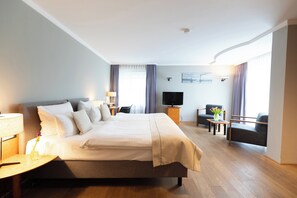 Habitación de hotel con una cama grande, televisión, escritorio y una silla.