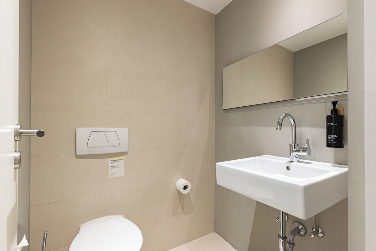 Une salle de bain avec un lavabo blanc, un miroir, des toilettes et un porte-serviettes.