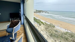 Ein Zimmer mit großem Fenster und Blick auf einen Strand.