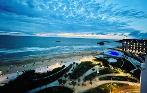 Un hotel frente al mar con vista a la playa, piscina y jardines ajardinados.