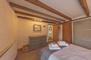 Un dormitorio con una cama, un aparador, un espejo y un armario de madera.