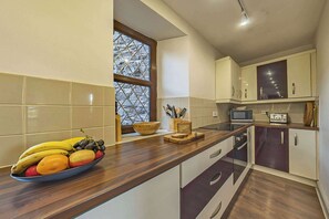 A modern kitchen with wooden countertops, a bowl of fruit, and a window with a view.