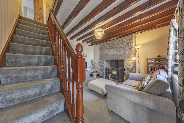 A staircase with wooden railings, a stone fireplace, a sofa, and a bookshelf in a living room.