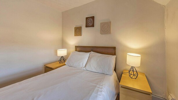 Ein Hotelzimmer mit einem Einzelbett, zwei Nachttischlampen und drei Wandbildern.