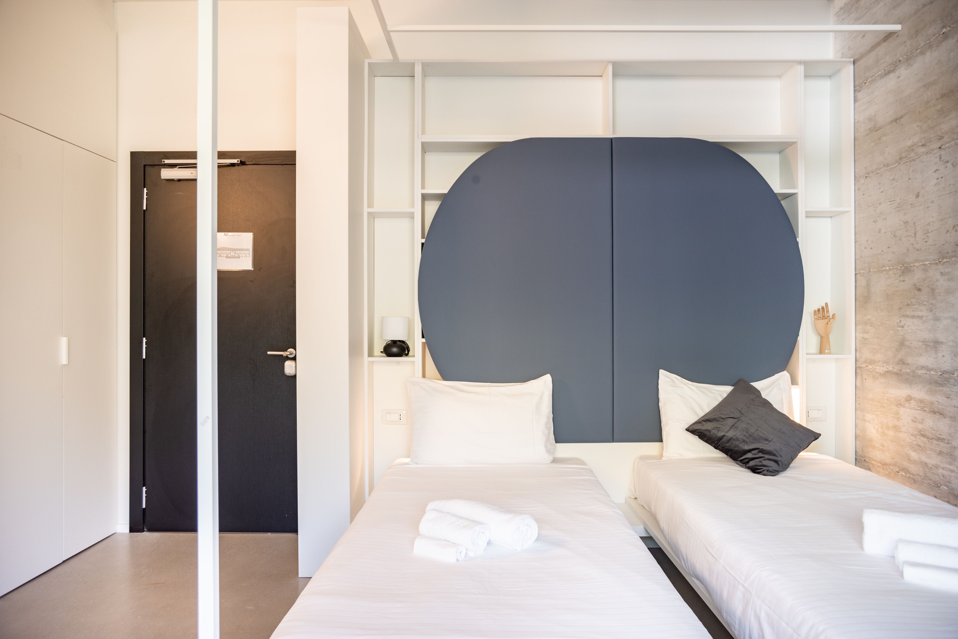 A modern hotel room with a large bed, a wardrobe, and a door.