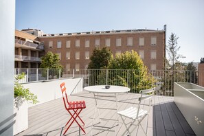 A balcony with a table and chairs, a railing, and a building in the background. - Camplus San Pietro - Casa per Ferie (Rome)