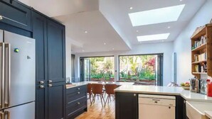 Een moderne keuken met donkere kastjes, een houten vloer en een groot eiland.