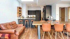 Een moderne keuken met donkere kastjes, een houten eettafel en barstoelen.