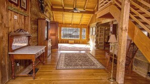 Un intérieur spacieux en bois, avec un plafond haut, une grande fenêtre et un escalier.