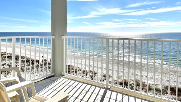 A covered balcony with a view of a beach and ocean.