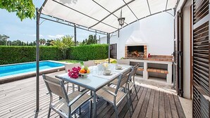 An outdoor patio with a table set for dining, a barbecue grill, and a swimming pool. - Villa Provenza, Cozy villa with pool near Port Pollensa (Port de Pollença)