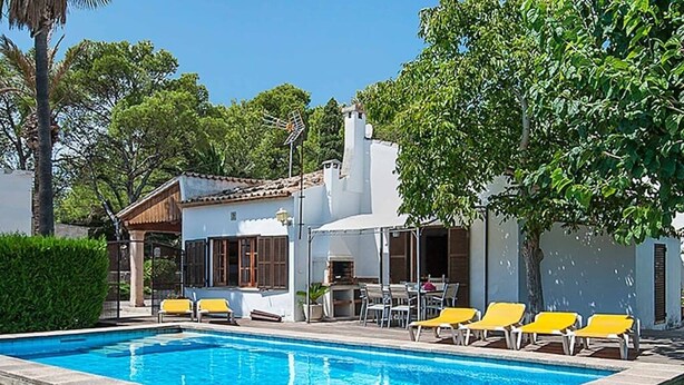 A swimming pool with yellow lounge chairs and a patio area with a table and chairs. - Villa Provenza, Cozy villa with pool near Port Pollensa (Port de Pollença)